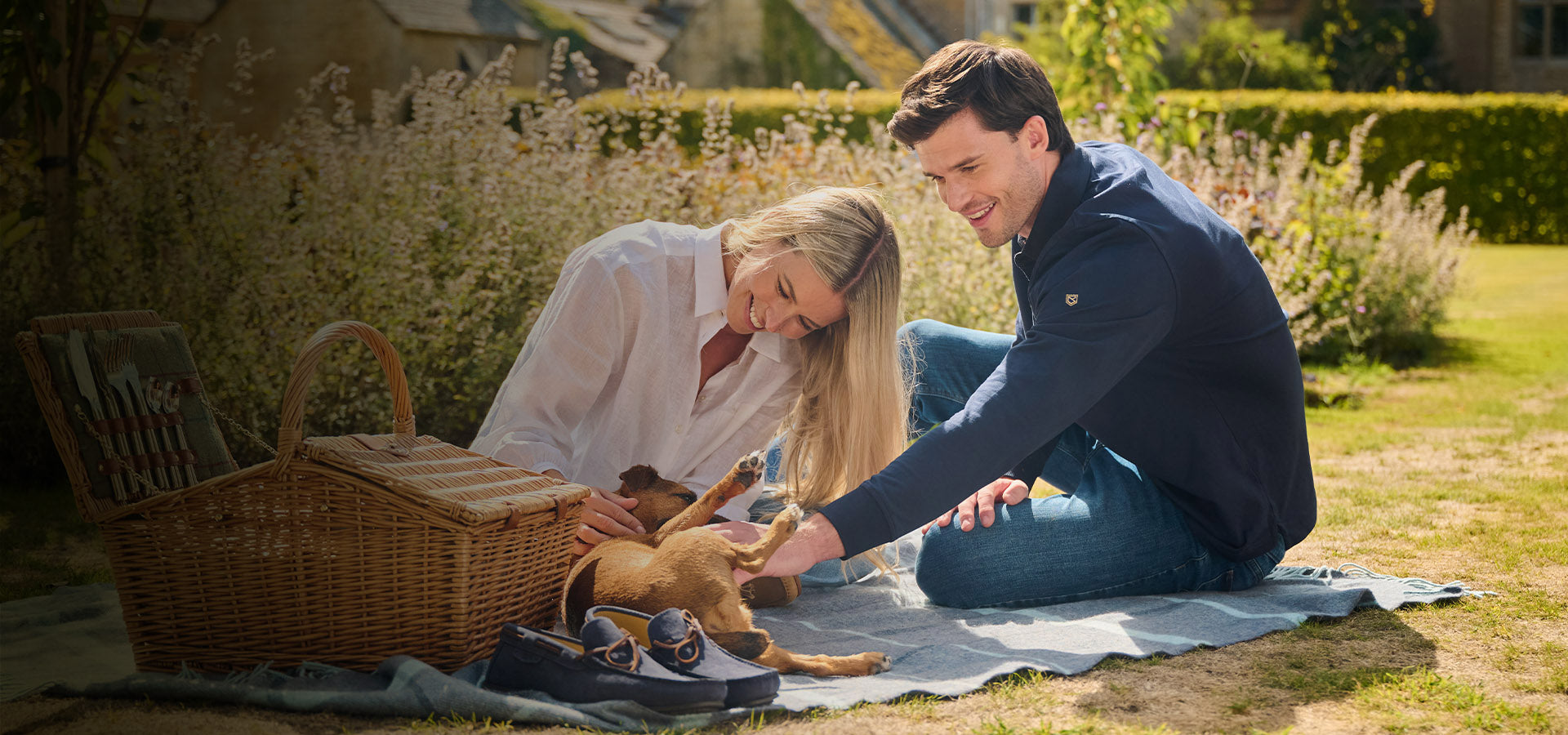 Couple with a dog sitting on a blanket in a garden