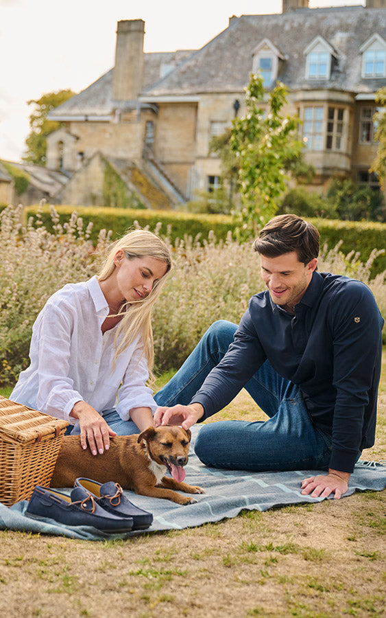 Couple sitting on a blanket with a dog in a garden setting