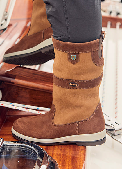 Brown leather boot with a visible brand logo on a wooden surface.