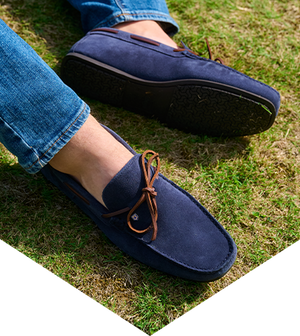 Navy loafers with brown laces worn on grass