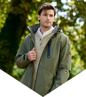 Man wearing a green jacket with a fur-lined hood against a blurred natural background