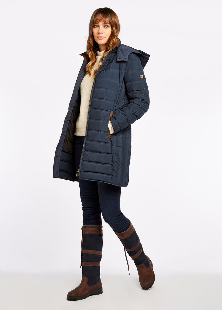 On model image of a woman wearing a pair of Dubarry womens knee-high navy and brown leather Galway Country Boot with laced top. She is also wearing a navy quilted jacket, cream knitted jumper and a pair of navy honeysuckle jeans.