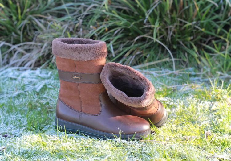 Outdoor image of a Pair of Dubarry Foxrock Country boots, walnut coloured fur lined boots in a grassland