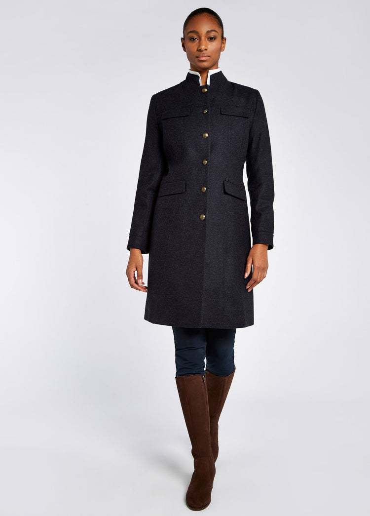 A woman modelling Dubarry women's Coolepark Tweed Navy Coat with button front style, double front splits and pocket flaps. She is also wearing navy honeysuckle jeans and brown boots.