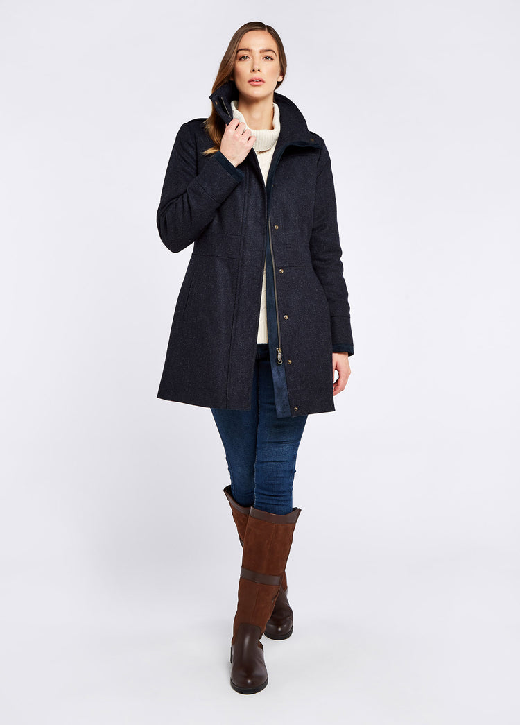 Woman modelling Dubarry women's Hedgerow Tweed Navy Coat with a two-way, civered centre front zip and vertical pockets. She is also wearing a white jumper, jeans and boots.