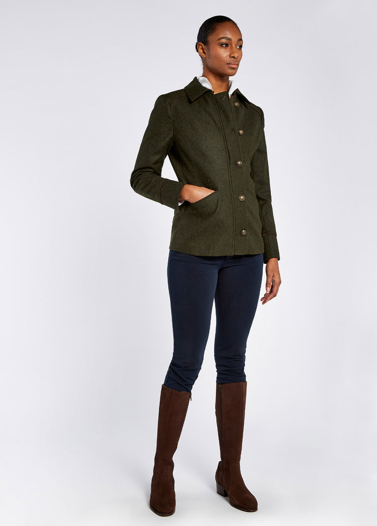 A woman modelling Dubarry women's Slievebloom Tweed Loden Coat with buttons, collar and signature lining. The model is also wearing navy honeysuckle trousers and brown boots.