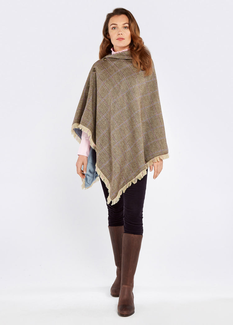 A woman modelling Dubarry women's Hazelwood Tweed Woodrose Poncho. She is also wearing black pants and brown boots.