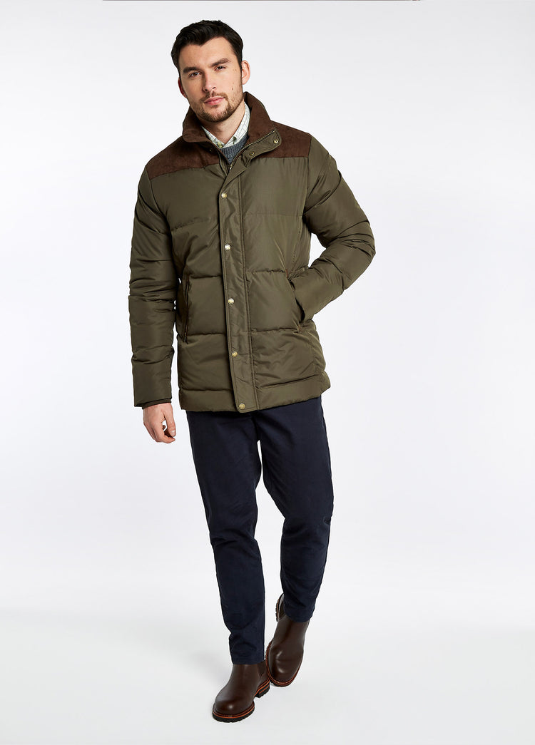 On model image of a man wearing Country Boot A pair of Dubarry Offaly ankle boots, mahogany brown coloured men's seude look cleated chelsea boots with elasticated side gussets and leather finger pulls, green quilted jacket and a pair of navy trousers.