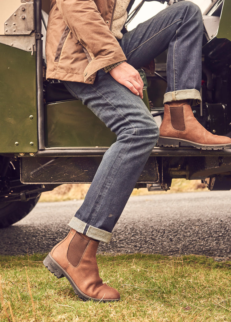 On model image of a man wearing a pair of Dubarry Antrim Walnut coloured leather country boots, men's Chelsea style boot in an outdoor setting.