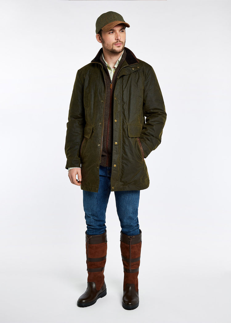 On Model image of a man wearing wider calf fitting Dubarry Men's knee-high walnut brown leather Galway Country Boot with laced top. He is also wearing a green wax jacket, brown knitted jumper, checked shirt, green and brown cap and a pair of denim jeans.