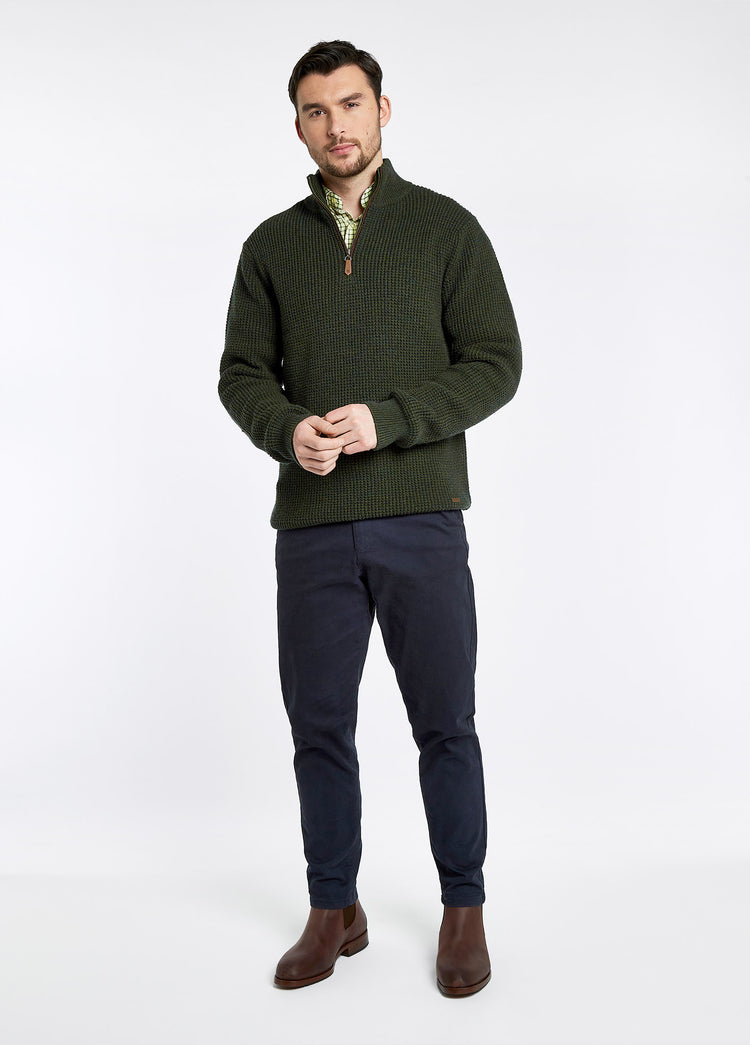 On model image of a man wearing a pair of Dubarry Kerry Chelsea ankle boots for men, old rum brown coloured leather with elasticated side gussets with front and heel finger pulls. he is also wearing a green half zip fleece and navy trousers.